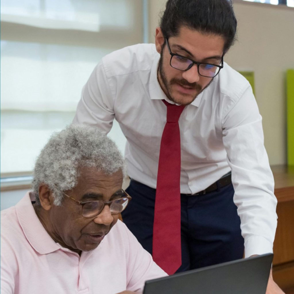 A council worker helps a local citizen to use a laptop